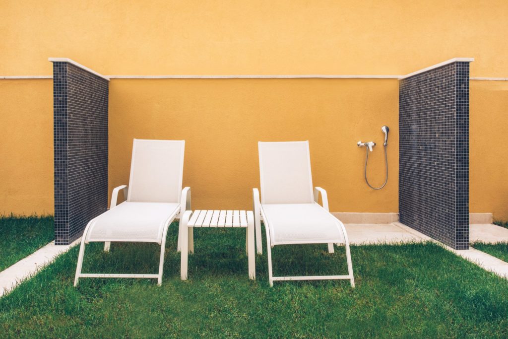 Two sun loungers and a shower in an outside harden
